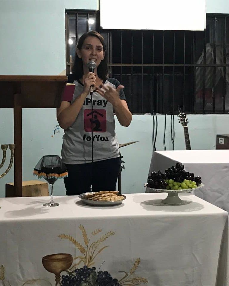 Virgínia falando durante um culto, ao lado do altar